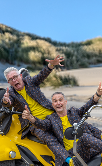 Mens 2 Producties zittend op gele trike op het strand staande afbeelding